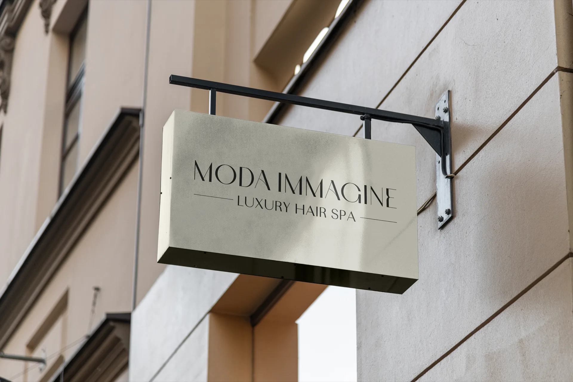 Insegna a bandiera avorio agganciata alla facciata con un braccio in ferro nero: sopra, in scuro, MODA IMMAGINE e sotto LUXURY HAIR SPA fra due filetti.