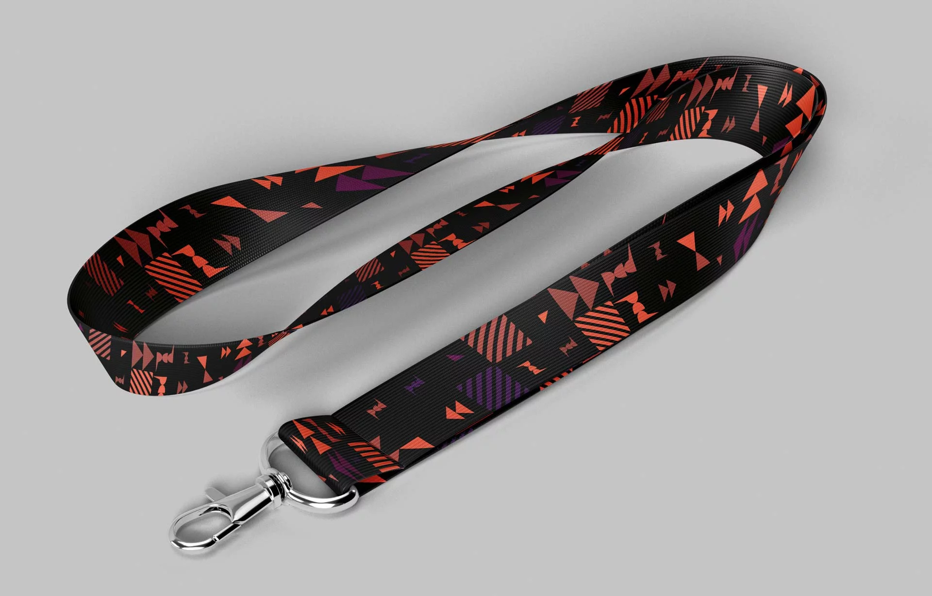 Nastro portabadge nero con moschettone, avvolto su un piano grigio, stampato con il pattern in arancione e viola.