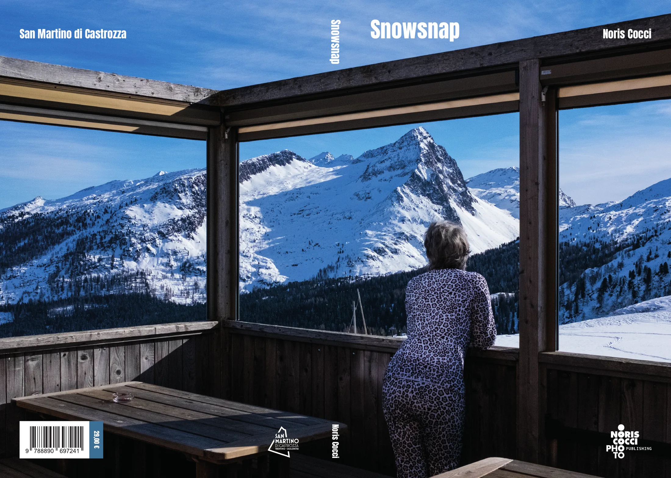 La copertina distesa, dalla quarta al fronte: una sola fotografia che gira tutto intorno, presa da dentro un rifugio con le vetrate aperte sulle Dolomiti innevate e una donna di spalle affacciata; titolo Snowsnap e nome dell'autore in bianco sul cielo, in quarta la scritta San Martino di Castrozza, il codice a barre e i marchi.